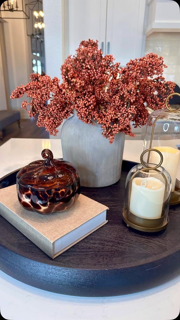 Dark wooden tray with a berry vase, pumpkin jar on a book, and candles.