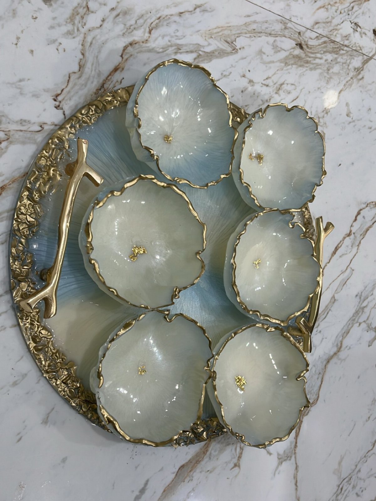 Gold-leaf-burled resin bowls on a matching decorative tray over a marble tabletop.
