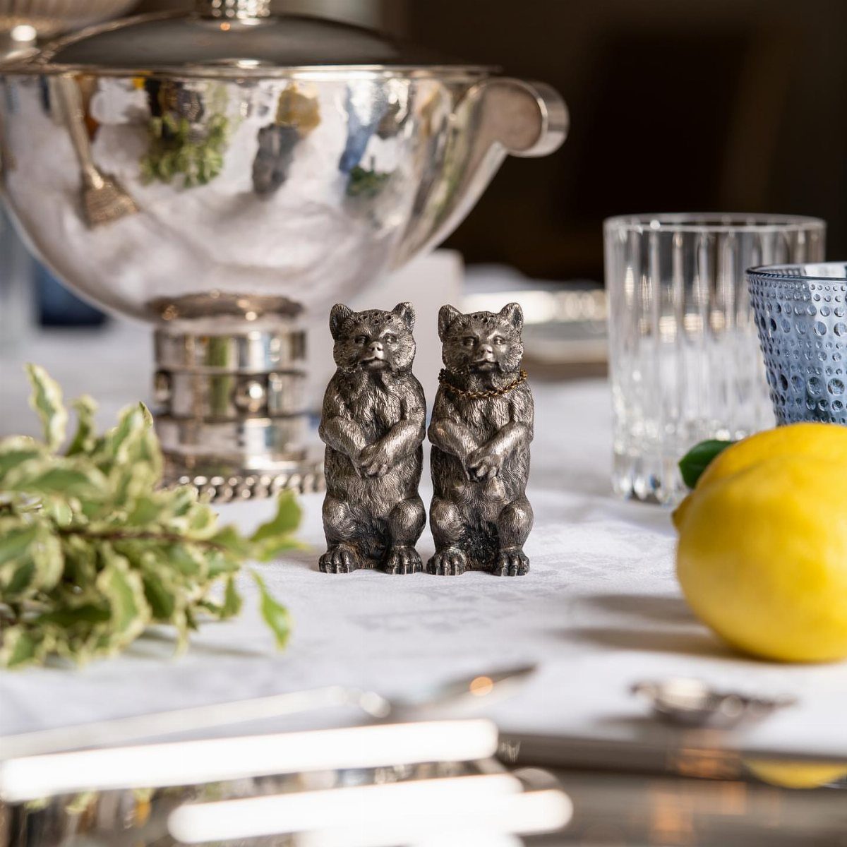 Two silver bear figurines acting as salt and pepper shakers on marble table
