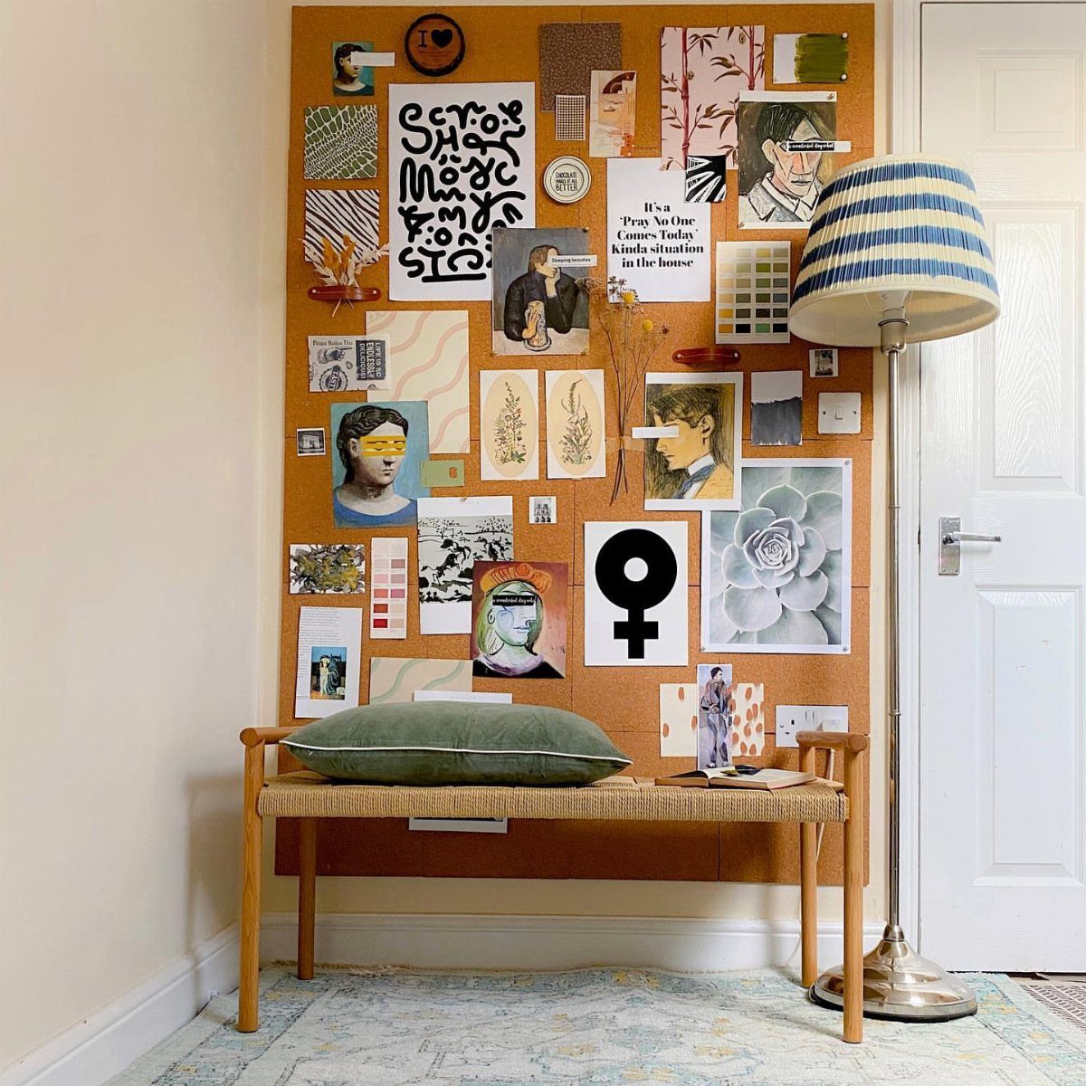 Large corkboard wall art filled with sketches and prints above a wooden bench.