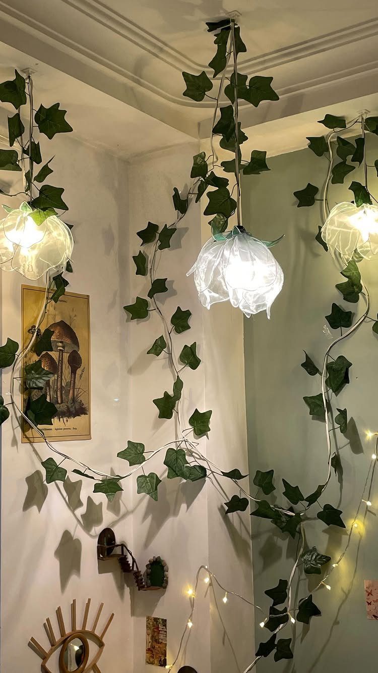 White paper lampshades hanging from the ceiling draped with green ivy vines