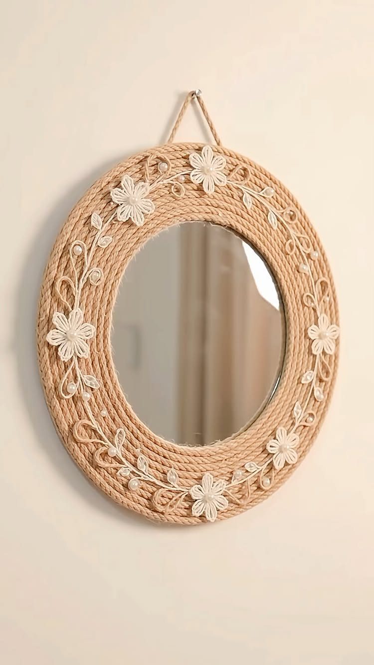 Round mirror with a beige rope-wrapped frame and white woven floral decorations.