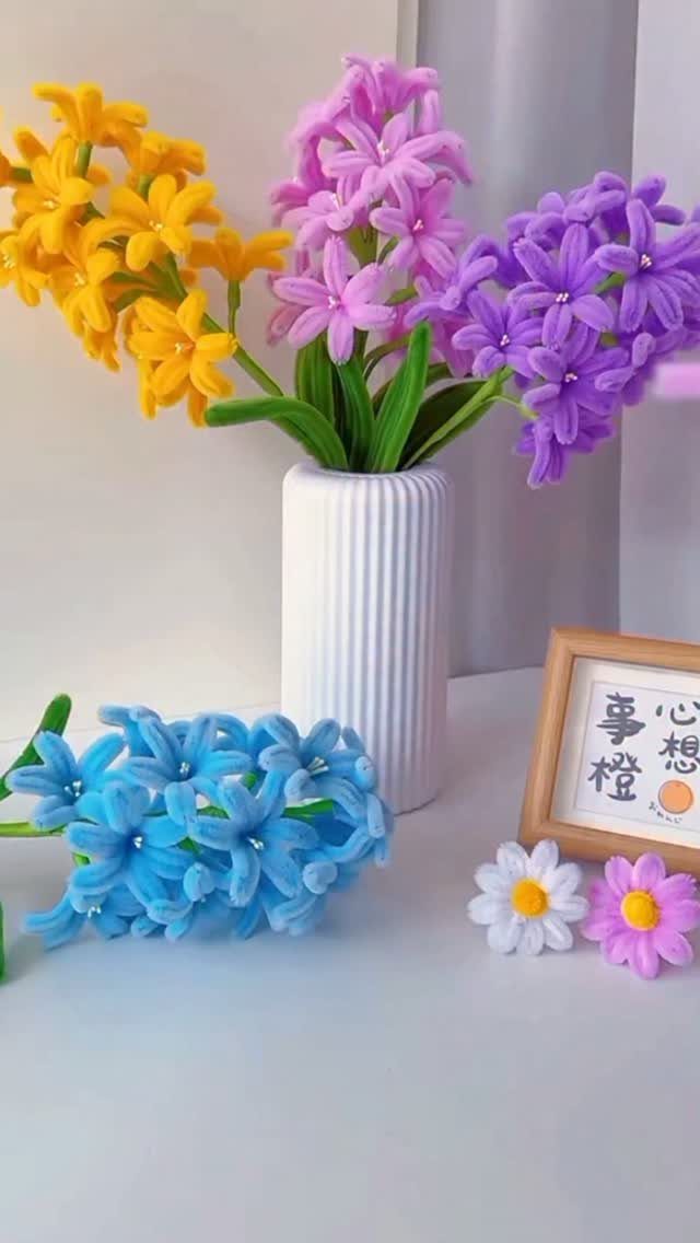Handmade fabric flowers in a white ribbed vase with a small wooden frame.