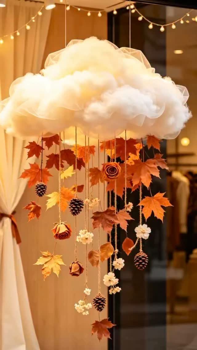 White fluffy cloud hanging decoration with autumn leaves and pinecones dangling below it.