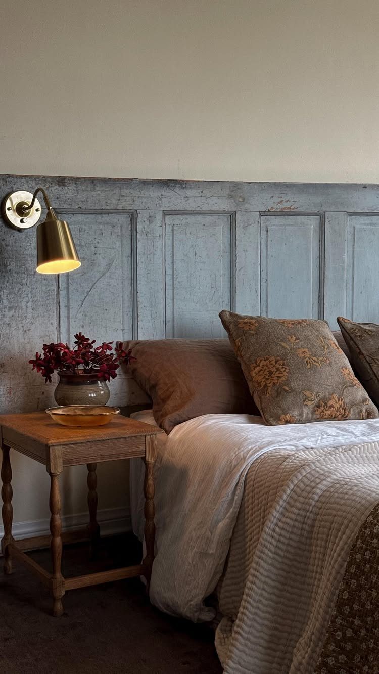 Light blue paneled wooden door used as a headboard behind a cozy bed