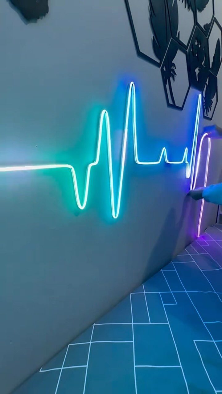 Blue neon heartbeat pulse light mounted on a grey wall with geometric flooring.