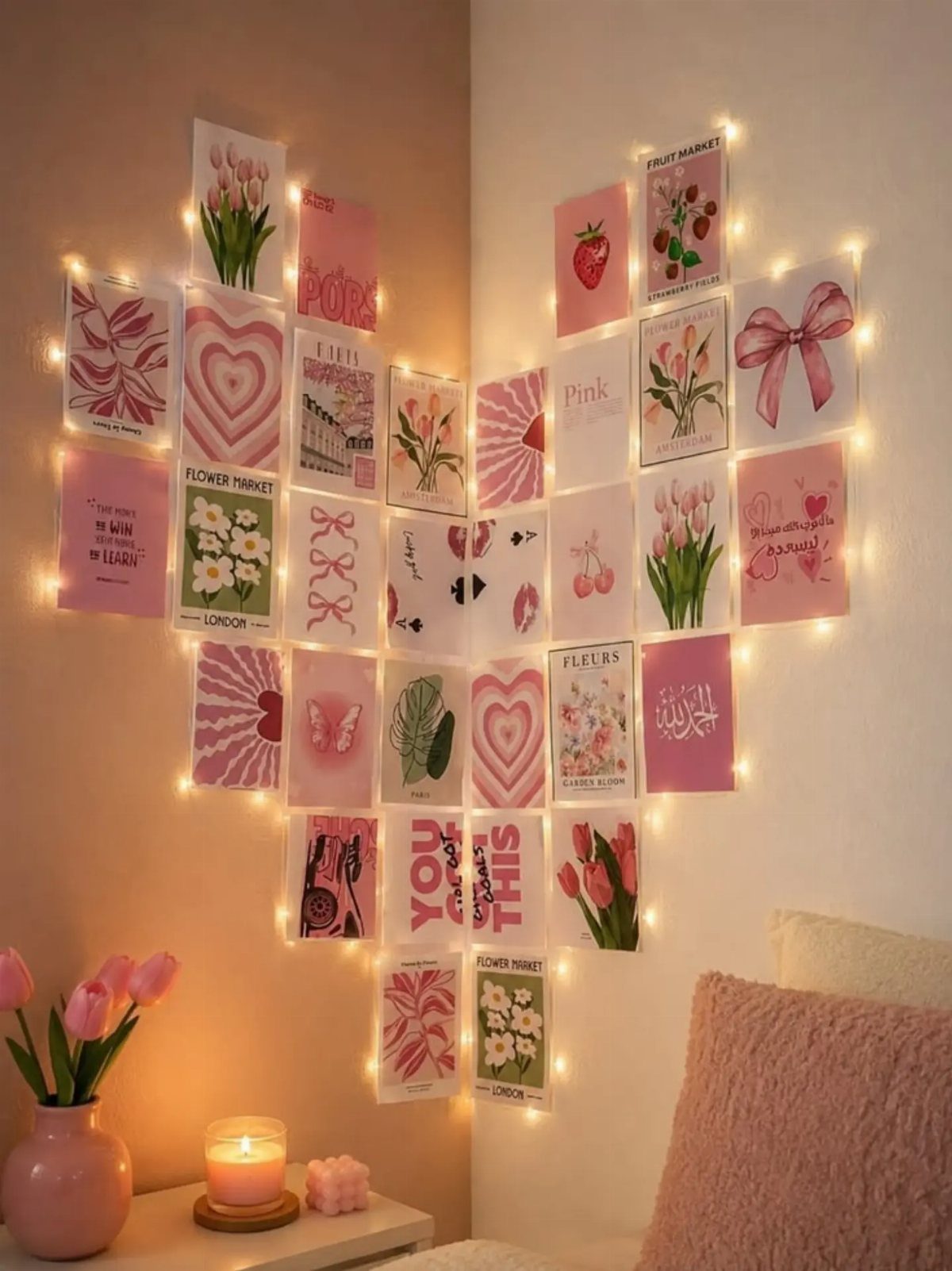 Pink aesthetic postcards and art prints hanging from fairy lights on a wall