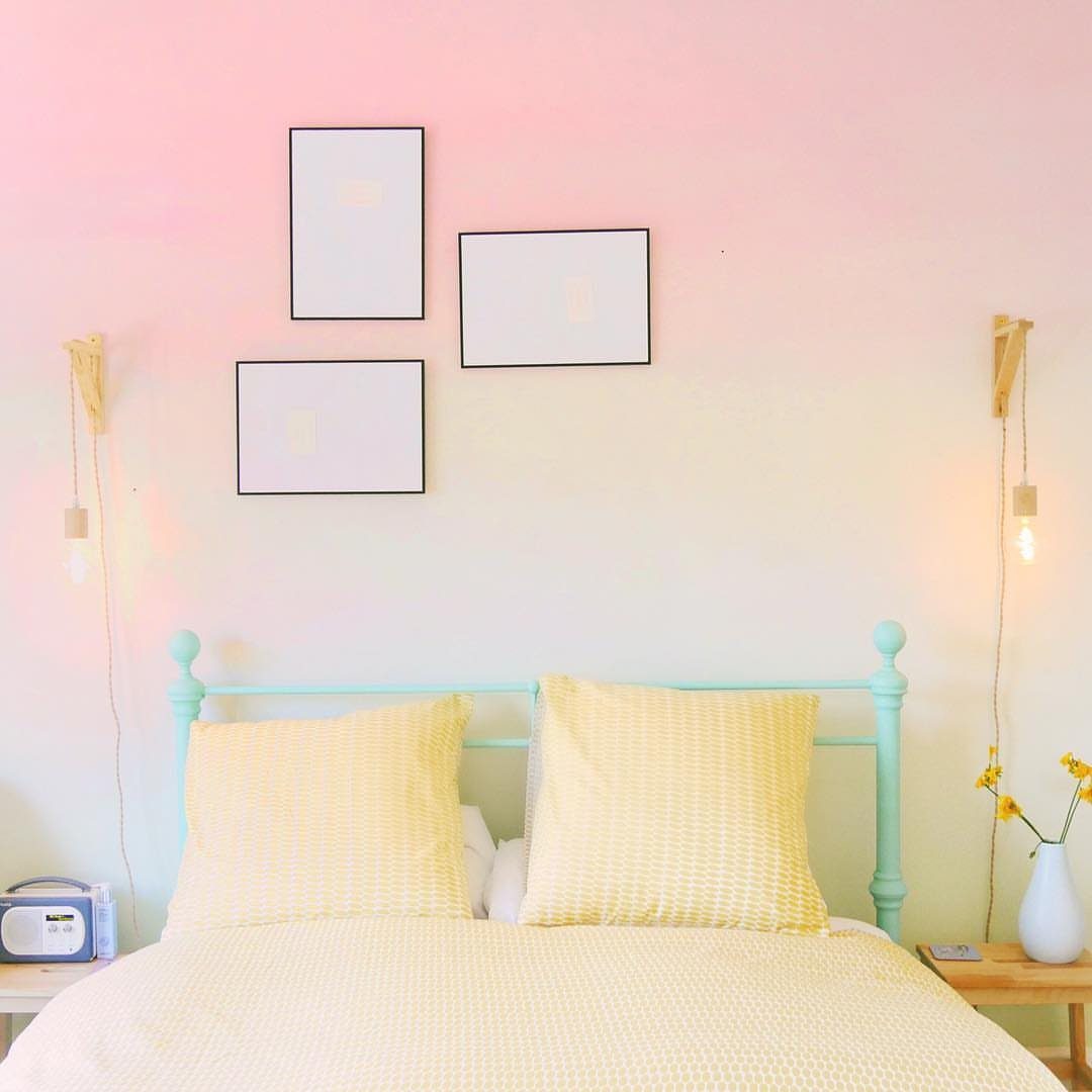 Bed with yellow pillows against a pink and white ombre gradient wall