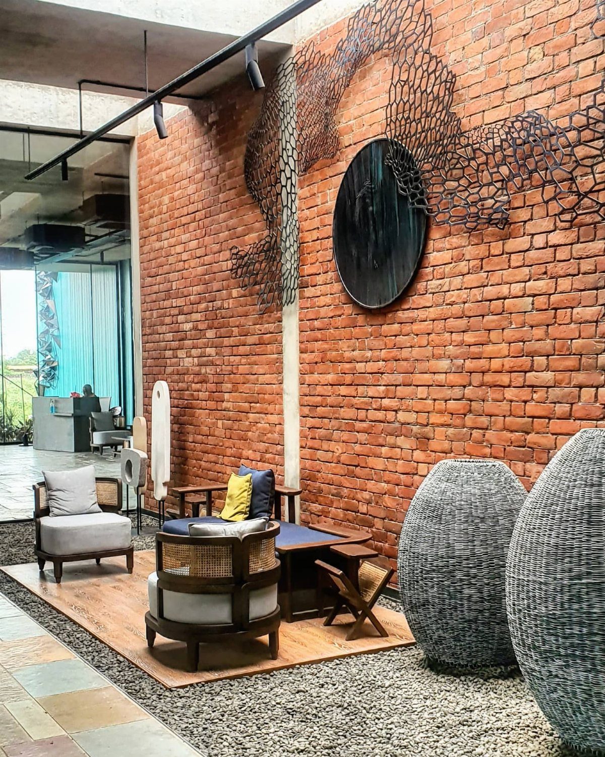 Circular black artwork and metal sculpture on a red exposed brick interior wall