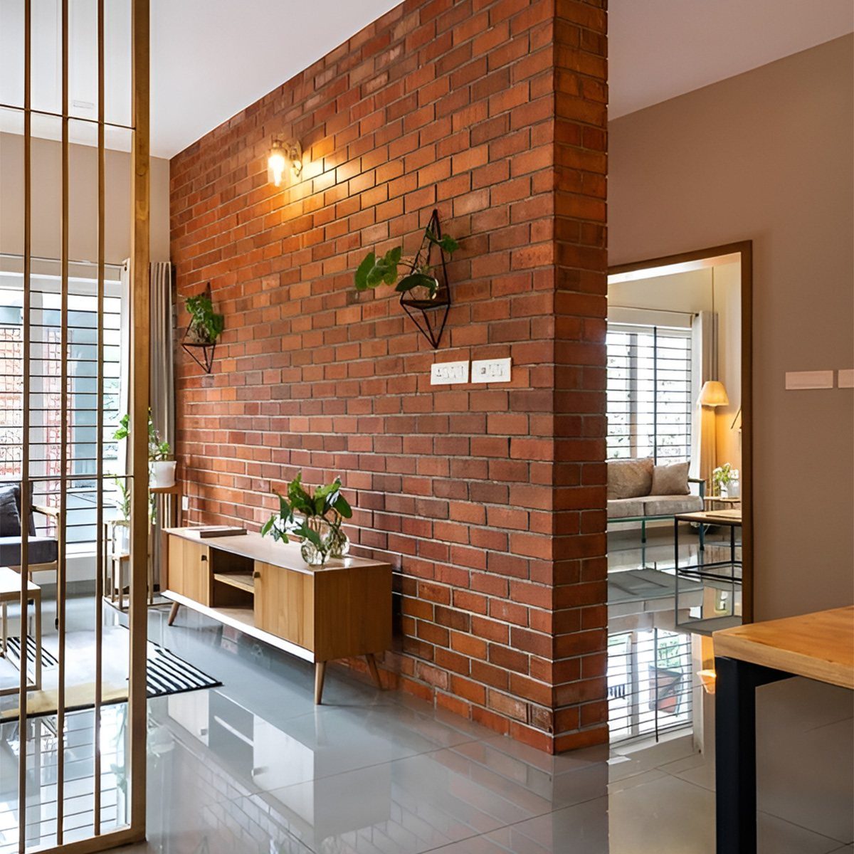 Red exposed brick accent wall with a wooden console and hanging plants.