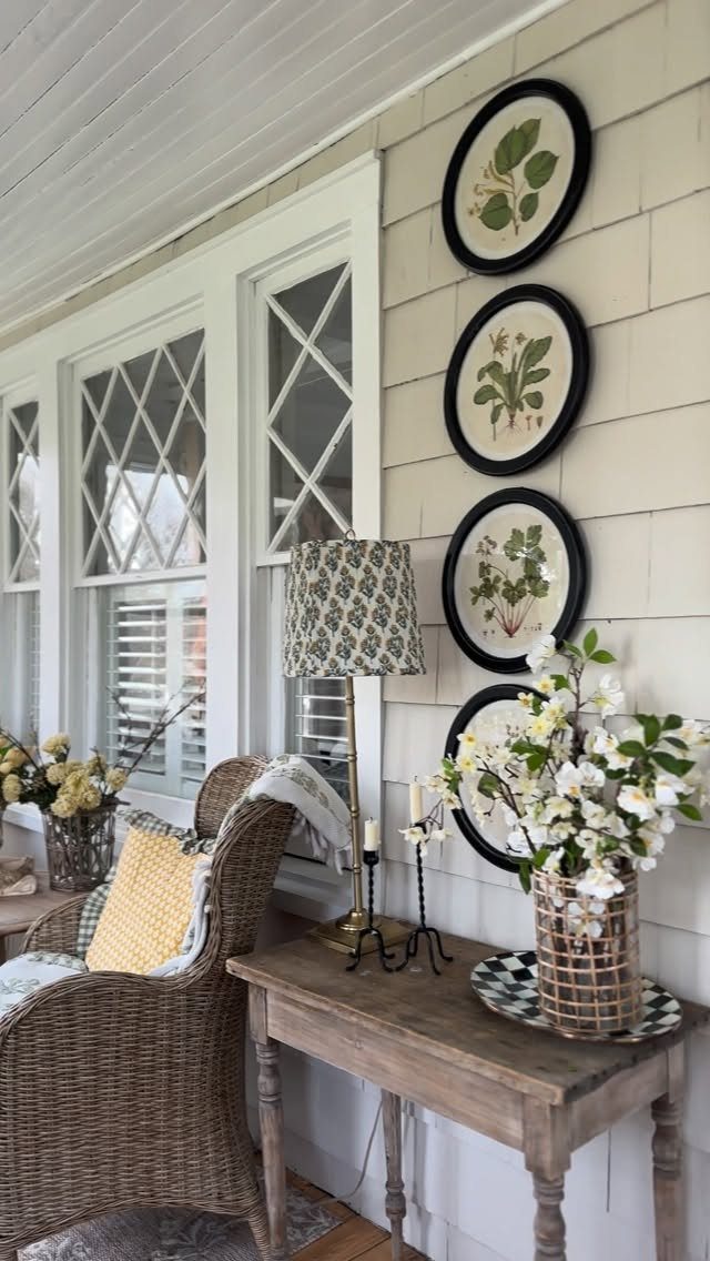 Four oval botanical prints hanging vertically on a light shiplap wall above a table.