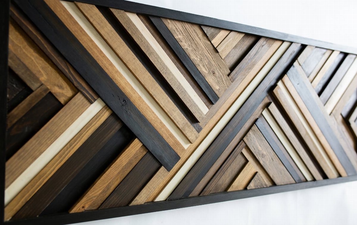Geometric wooden slat wall art in brown and black tones on white wall