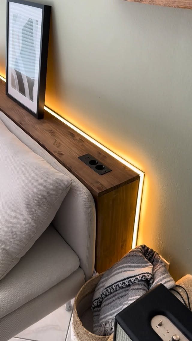 Wooden floating shelf with warm LED lighting installed behind a gray couch