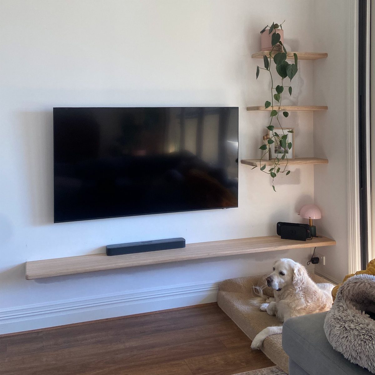 Wall-mounted TV with a long bottom shelf and vertical shelves on the right side.