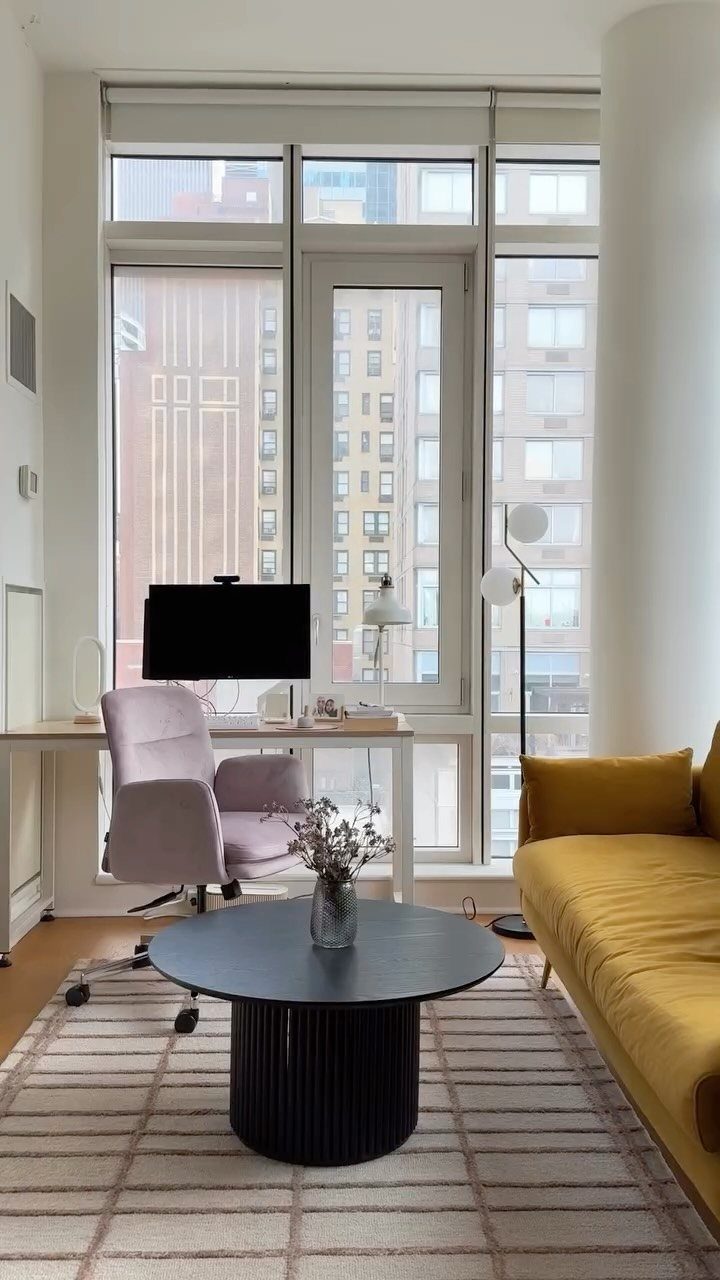 Modern apartment living room with floor to ceiling windows overlooking a city skyline.