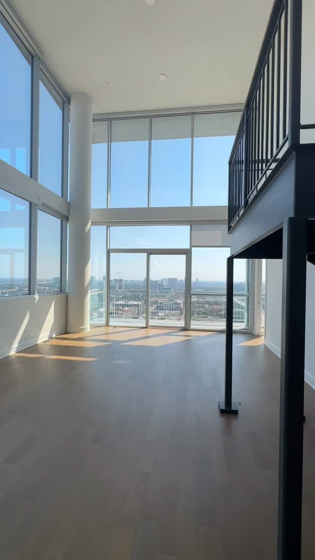 Empty modern apartment with floor to ceiling windows overlooking a distant city skyline