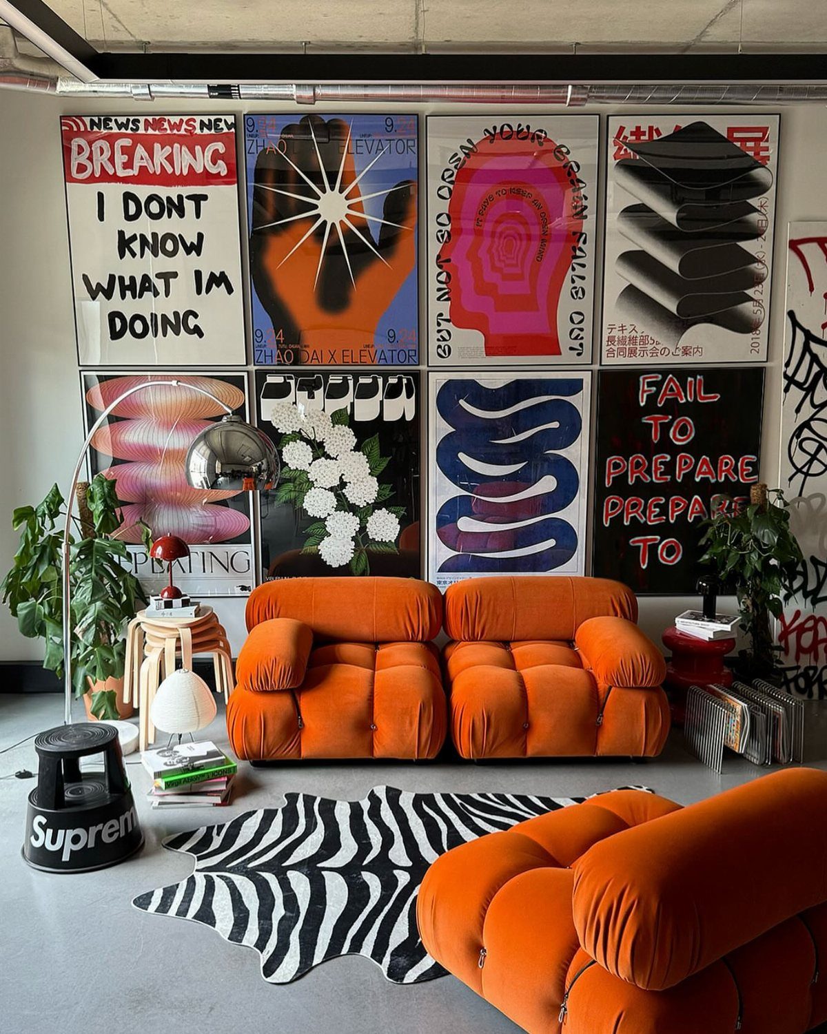 Orange modular sofa and zebra rug below a grid of colorful graphic art prints.