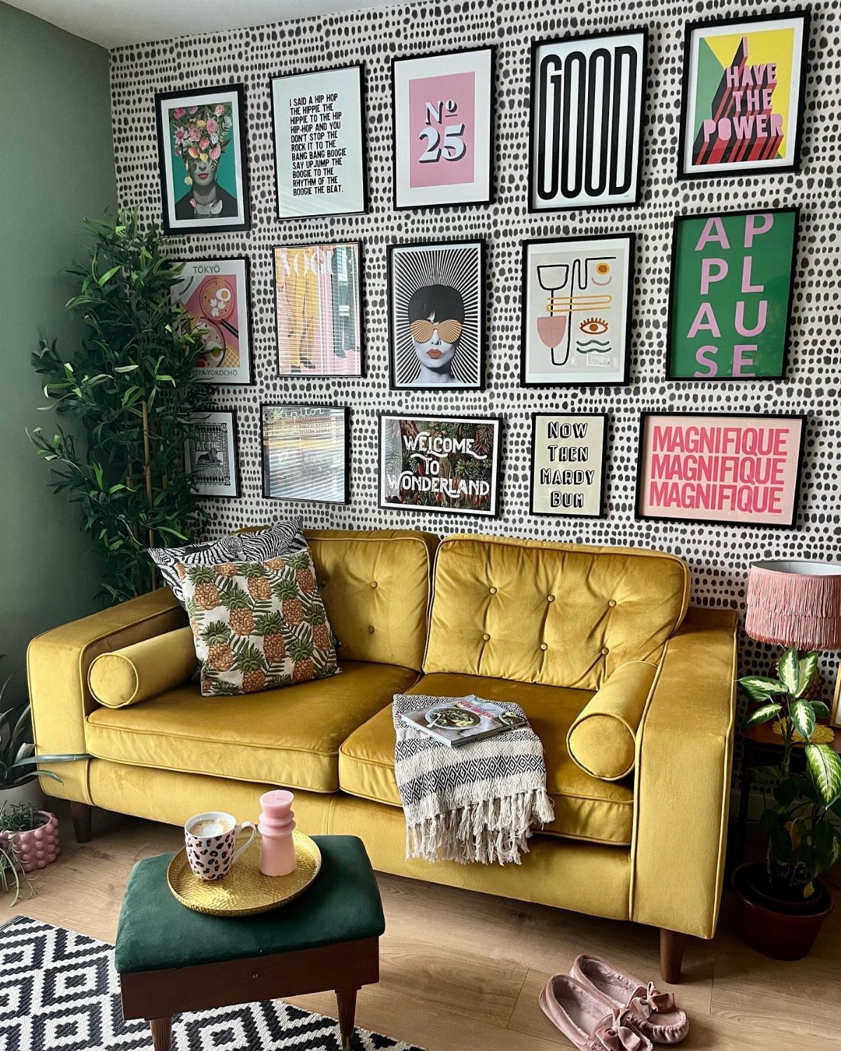 Yellow velvet couch with a gallery wall of framed art prints above it.