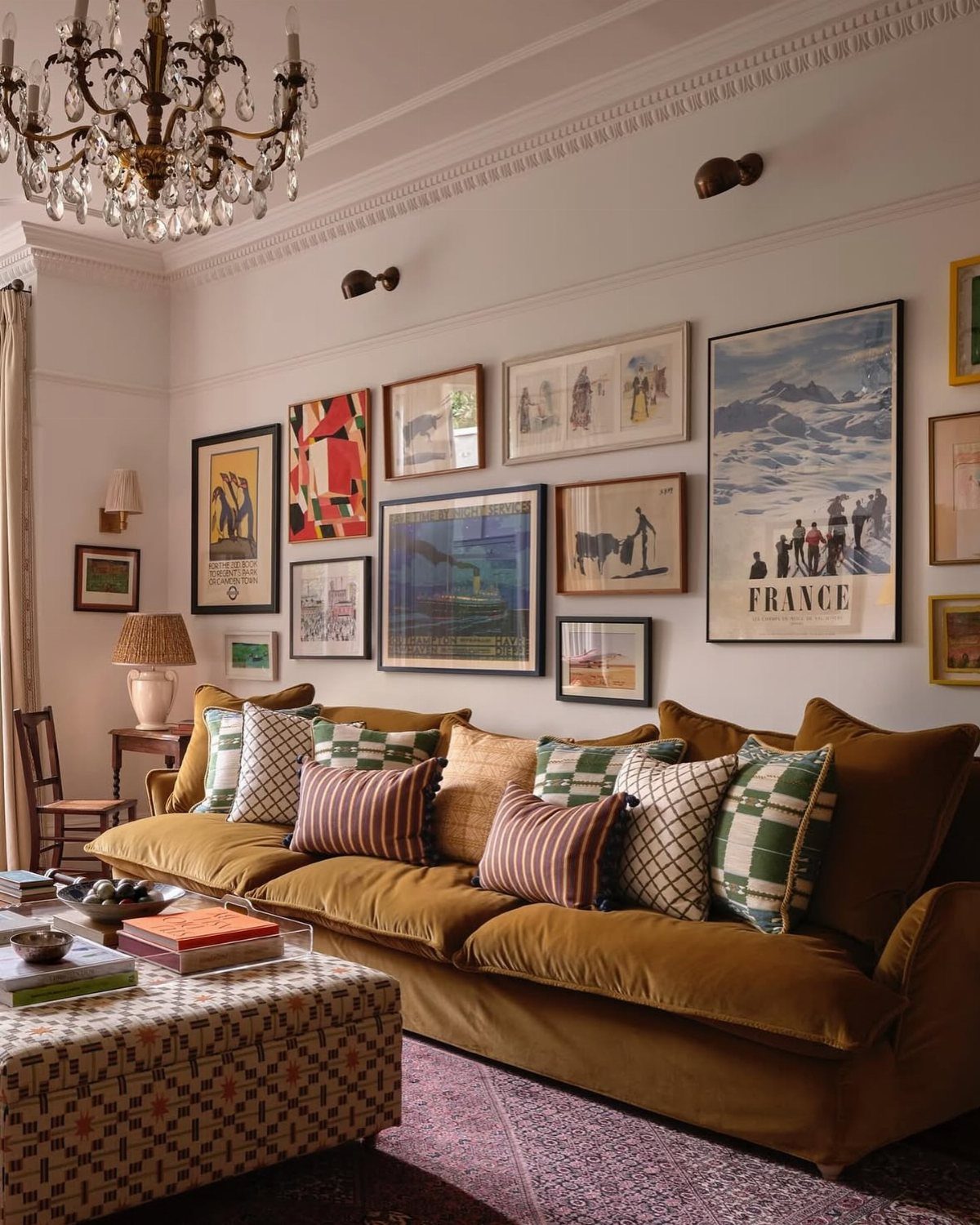 Mustard yellow velvet sofa beneath a diverse gallery wall of framed art prints.