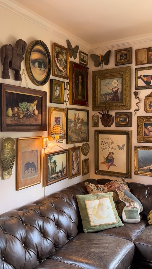 Brown leather tufted couch beneath a wall densely packed with eclectic framed art.