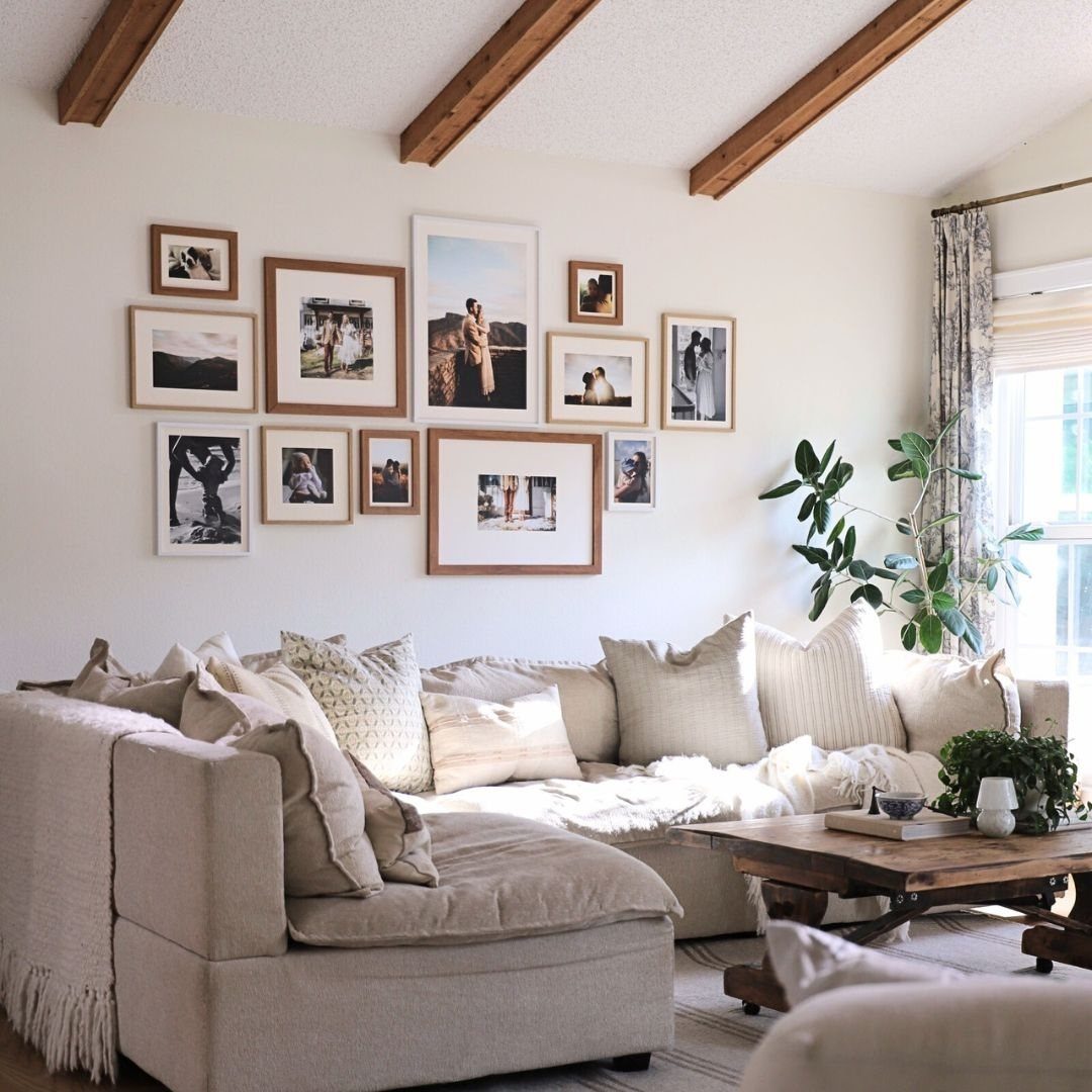 Gallery wall of framed photos hanging above a large beige sectional sofa.