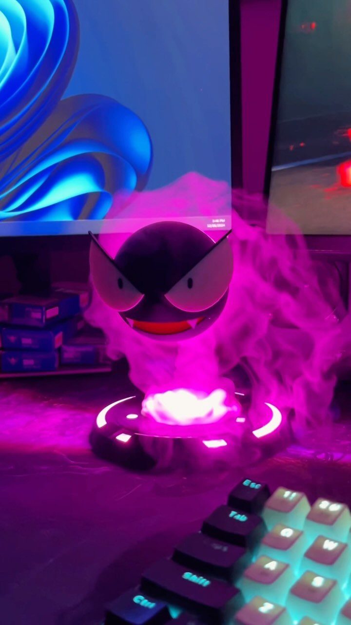 Gastly Pokemon figure with purple glowing smoke and base on a gaming desk