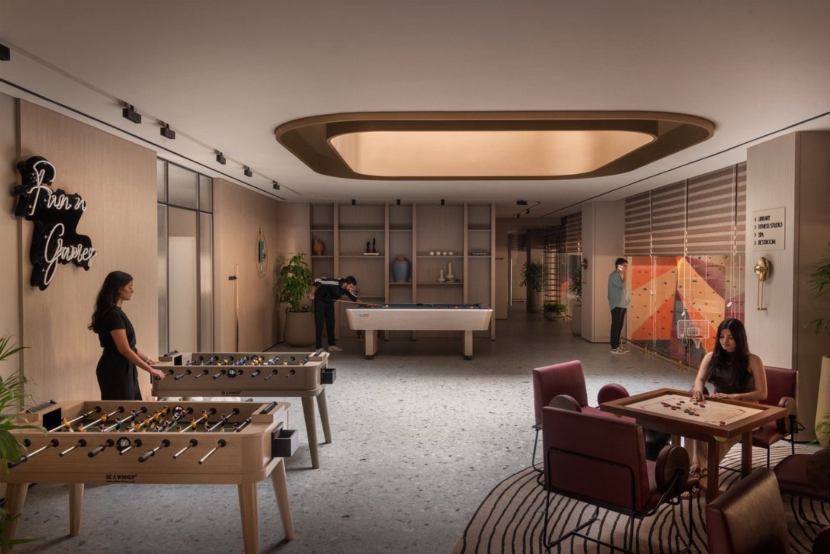 Modern games room with foosball and pool tables under a large oval ceiling light.