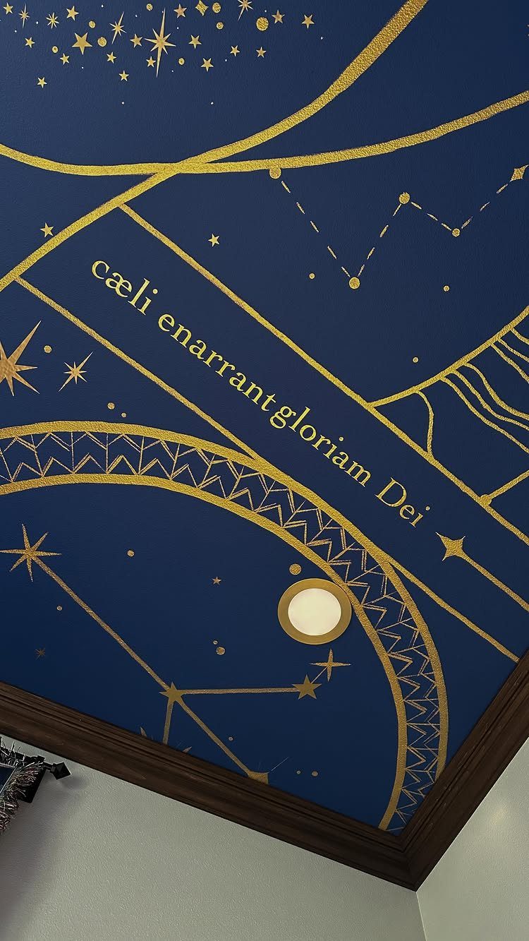 Dark blue ceiling with gold celestial paintings and Latin text near wooden molding