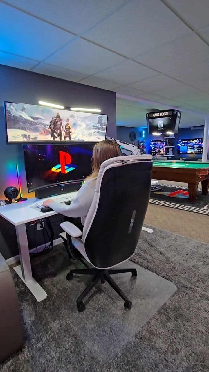 Person in a black and white gaming chair at a white desk in a games room