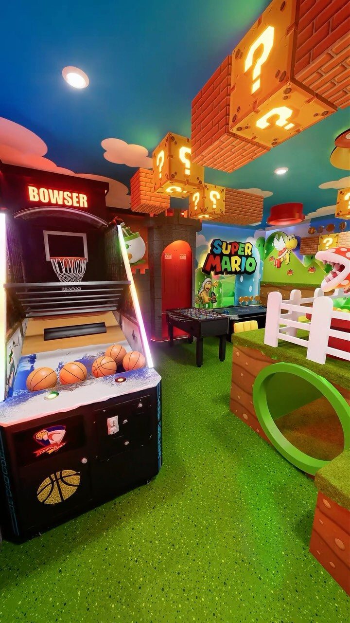 Super Mario themed game room with blue ceiling, green carpet, and arcade games.