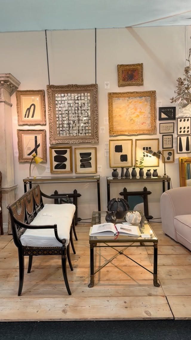 Vintage wooden settee and console tables with modern yellow lamps and framed art.