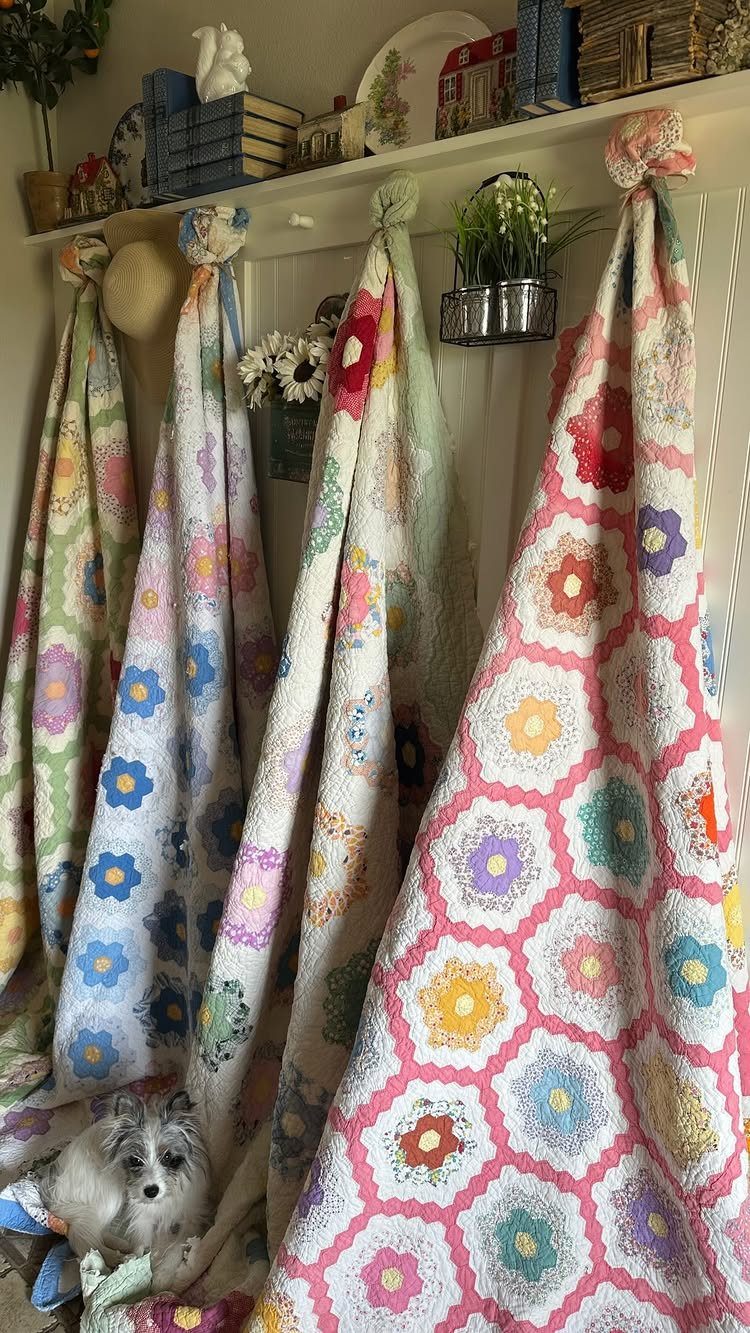 Colorful crocheted granny square blankets hanging from a shelf with a small dog.