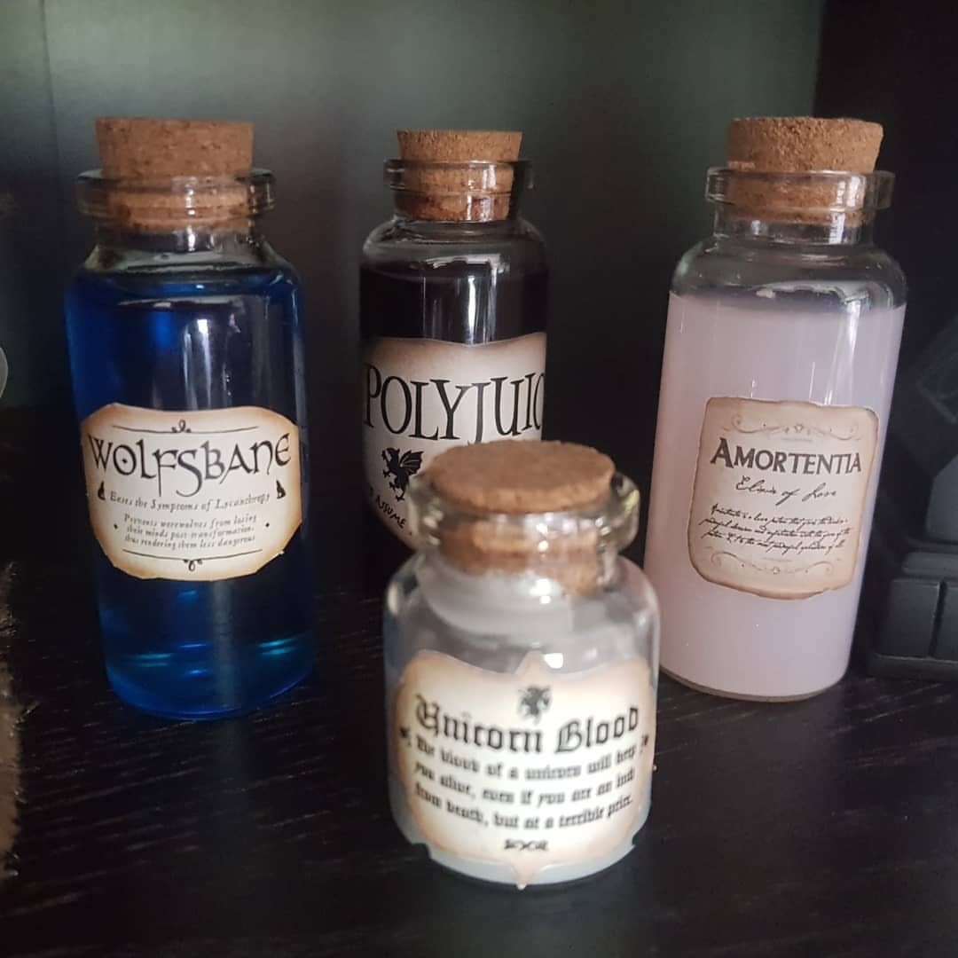 Four decorative potion bottles with corks and vintage labels on a dark surface.