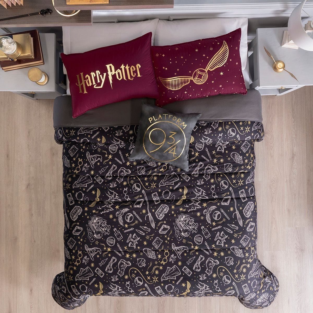 Harry Potter themed bedding with a black patterned comforter and maroon decorative pillows.