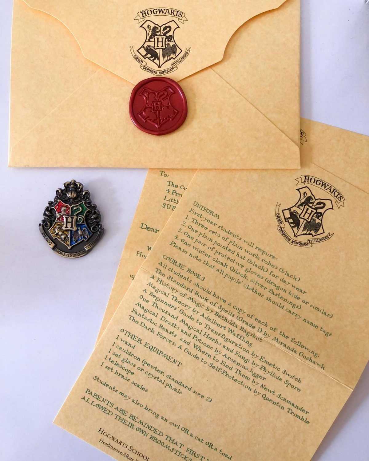Hogwarts acceptance letter and envelope with red wax seal and metal crest pin.