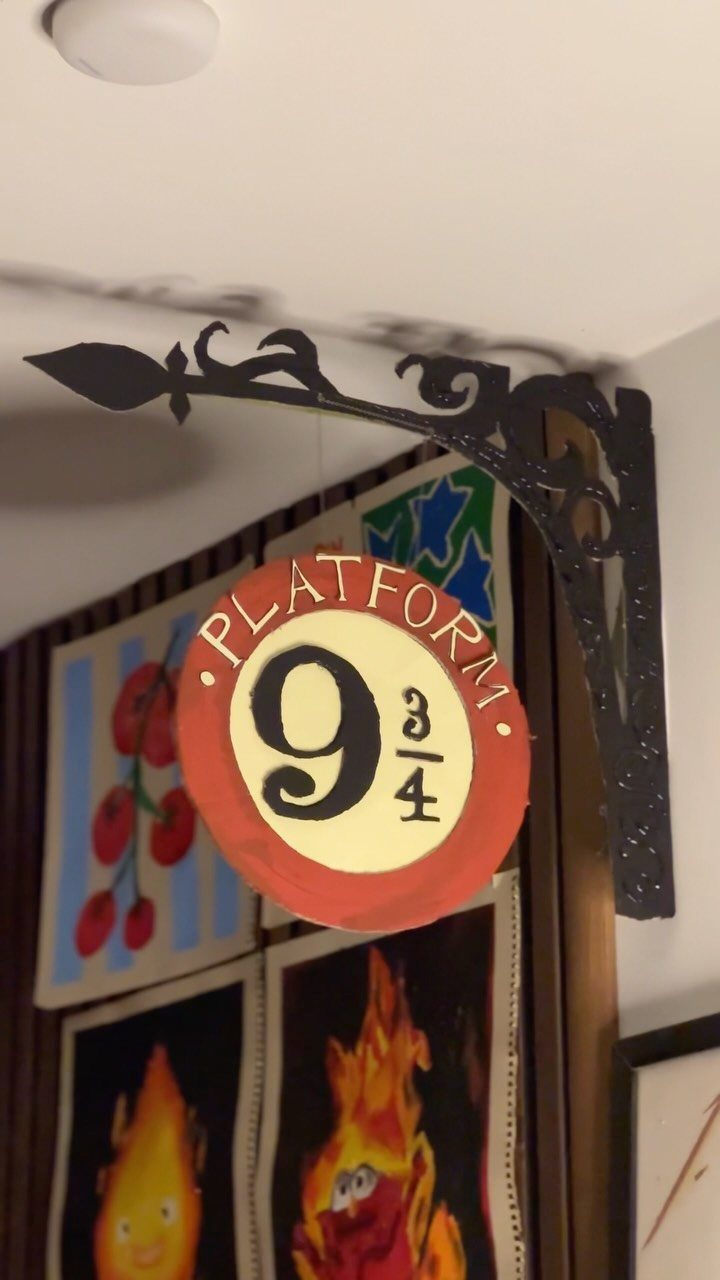 Platform 9 3/4 sign hanging from a black bracket in a decorated room.