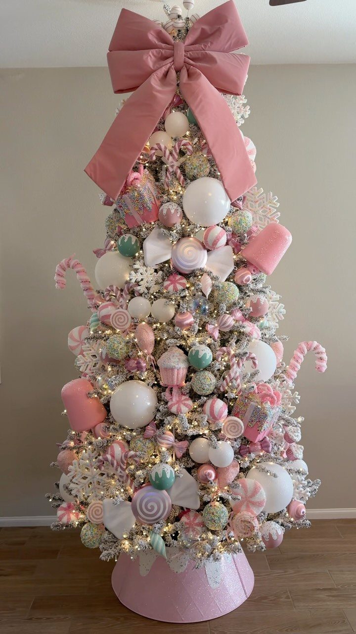 White Christmas tree decorated with pink and mint candy ornaments and a large bow