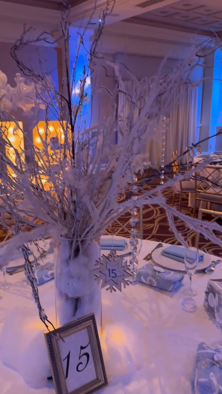 Frosted white branches and silver snowflake decor on a blue and white table.