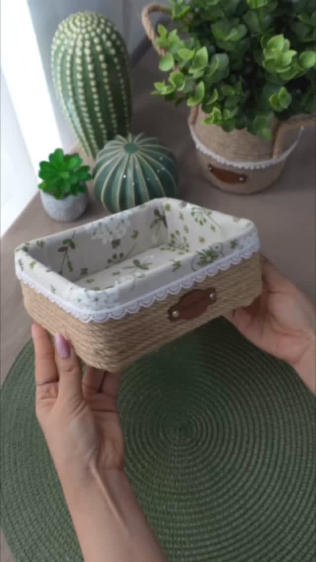 Woven decorative basket with lace trim and floral lining held by hands.