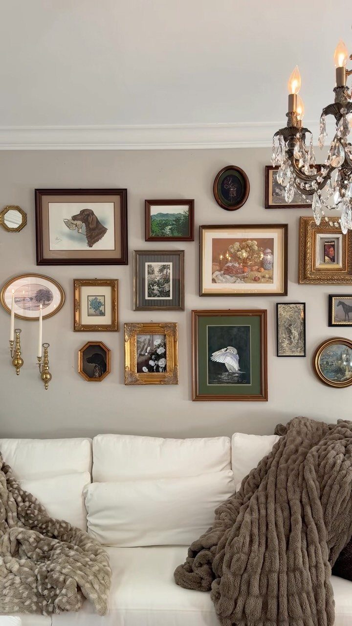 Gallery wall with assorted framed art above a white sofa with cozy blankets.