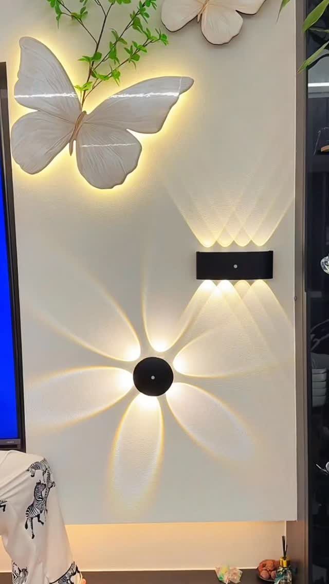 Black wall sconces casting light patterns on a white wall with butterfly lighting.
