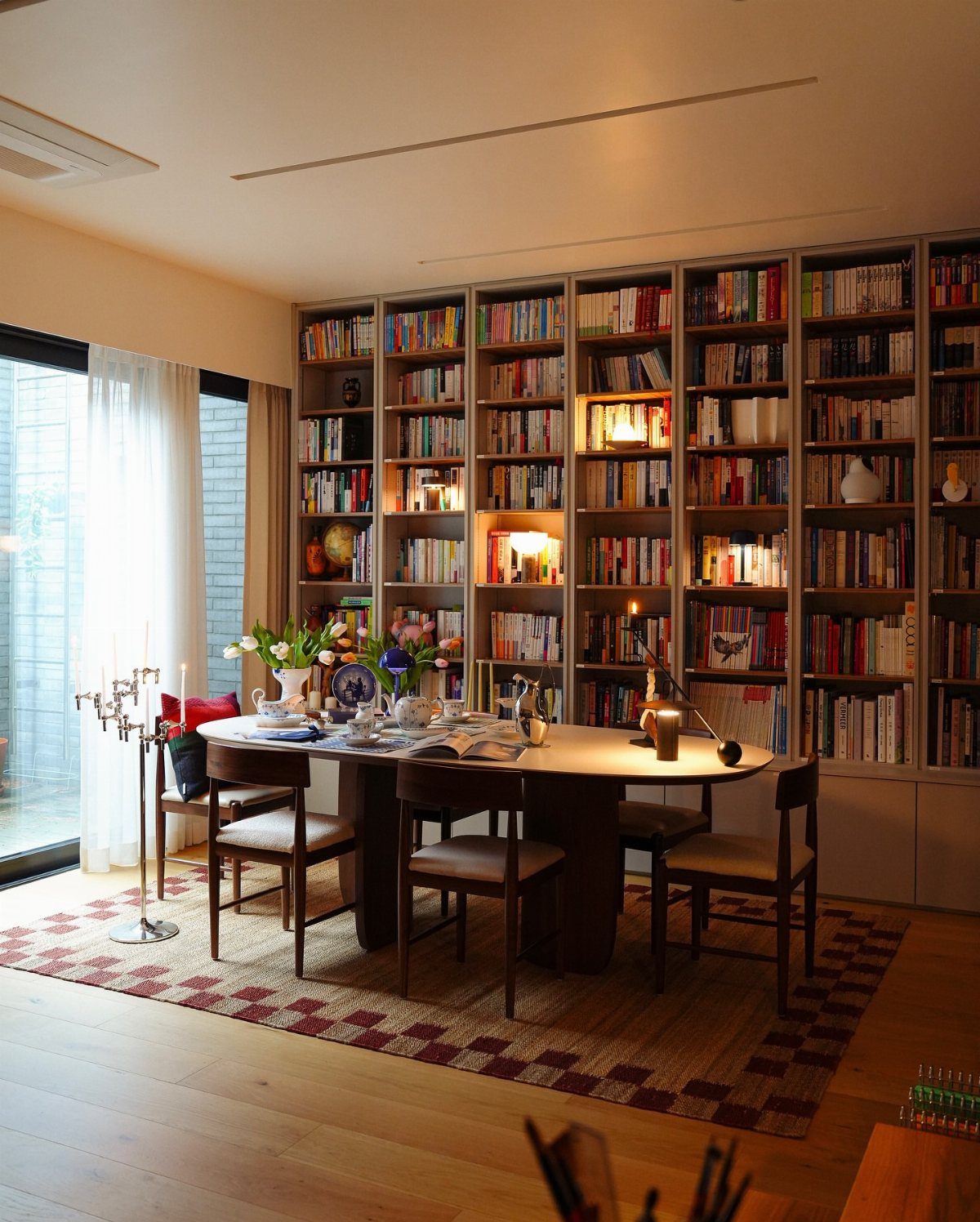 Dining table and chairs set against a wall of floor-to-ceiling bookshelves.