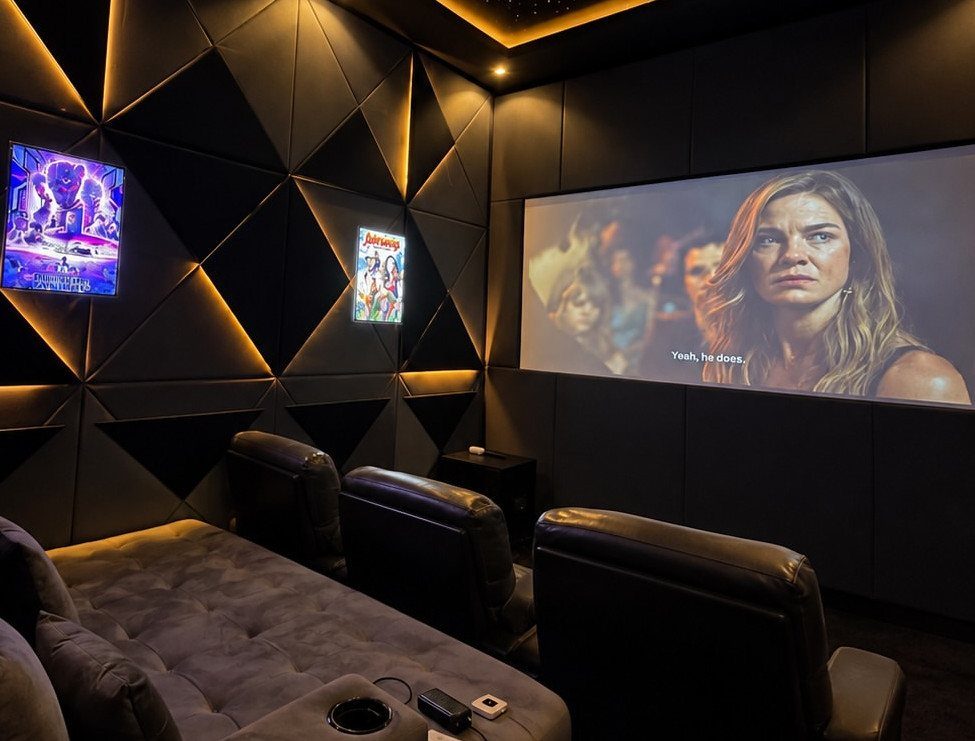 Home theater with black geometric backlit wall panels and leather reclining seats.