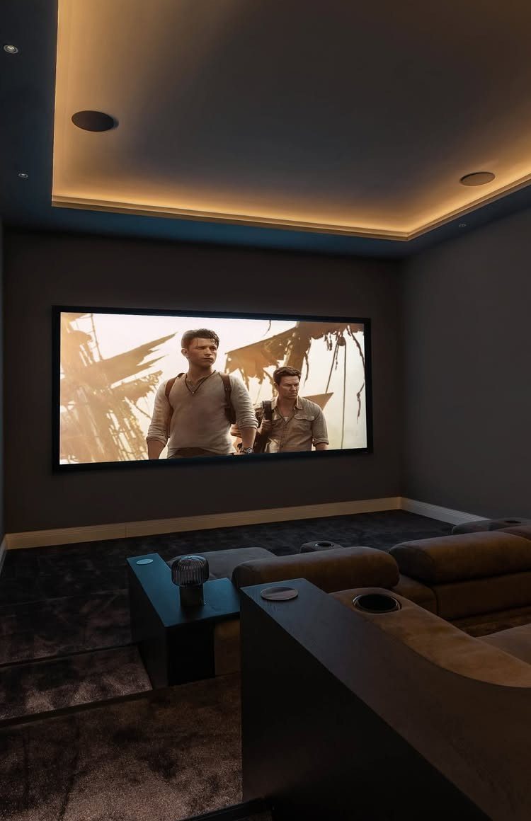 Home cinema room with a large movie screen, leather seating, and recessed ceiling lighting.
