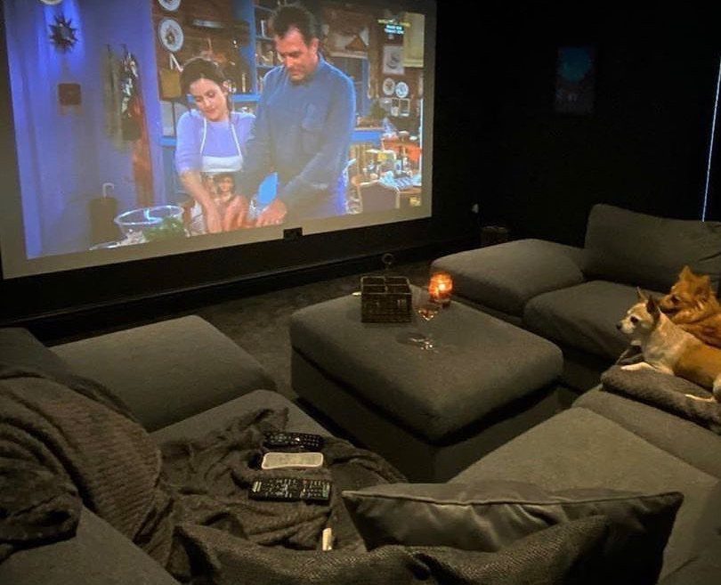 Grey sectional sofas and ottoman facing a large projection screen in a dark room