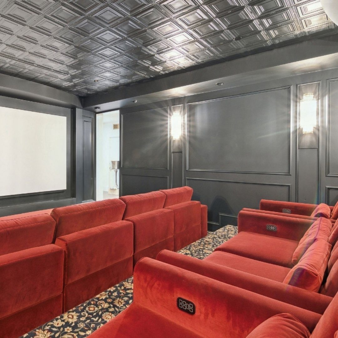 Red velvet theater seats in a room with dark walls and embossed ceiling