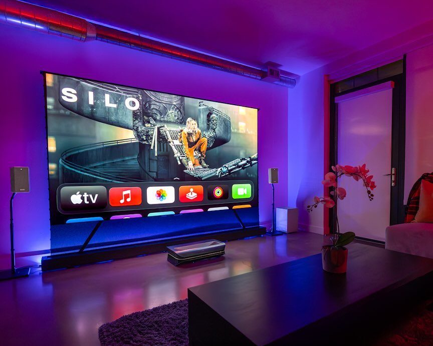 Home theater room with purple and blue ambient LED lighting and projection screen.