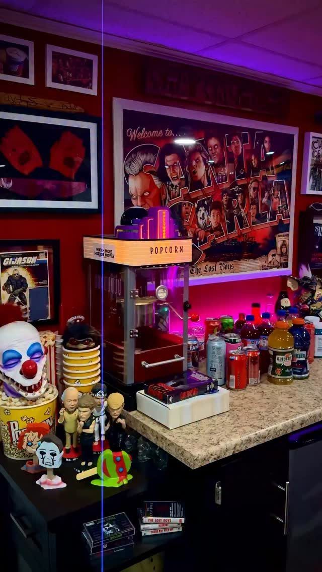 Framed movie posters on a red wall above a popcorn machine and collectibles.