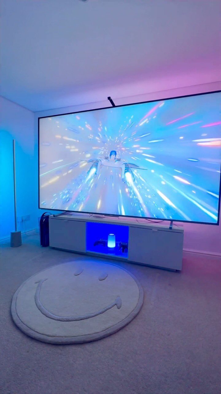 Large television screen with blue and purple ambient lighting and a smiley-face rug.