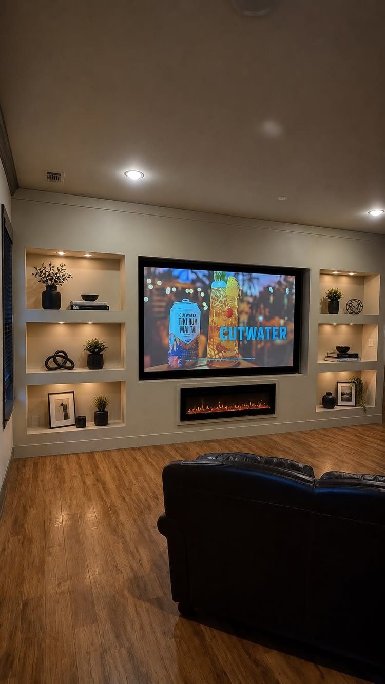 Home theater with a large screen, fireplace, and illuminated built-in display shelves.